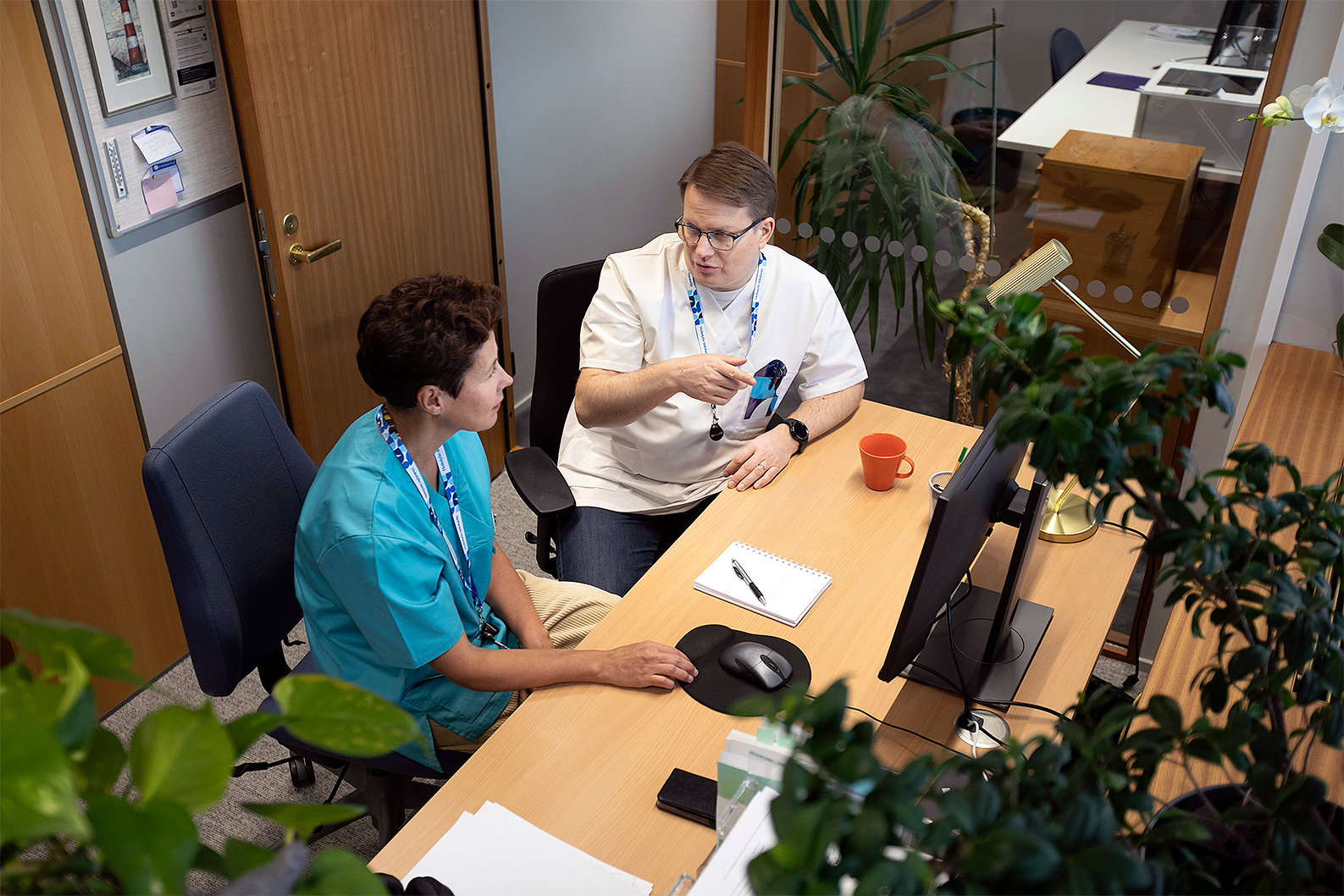 Kuura Health Oy -sivujen kansikuva. Kaksi terveydenhuollon asiantuntijaa keskustelemassa.