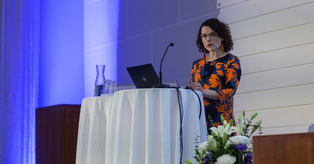 Hanna Tamminen lavalla, siniseksi heijastettu seinä taustalla.