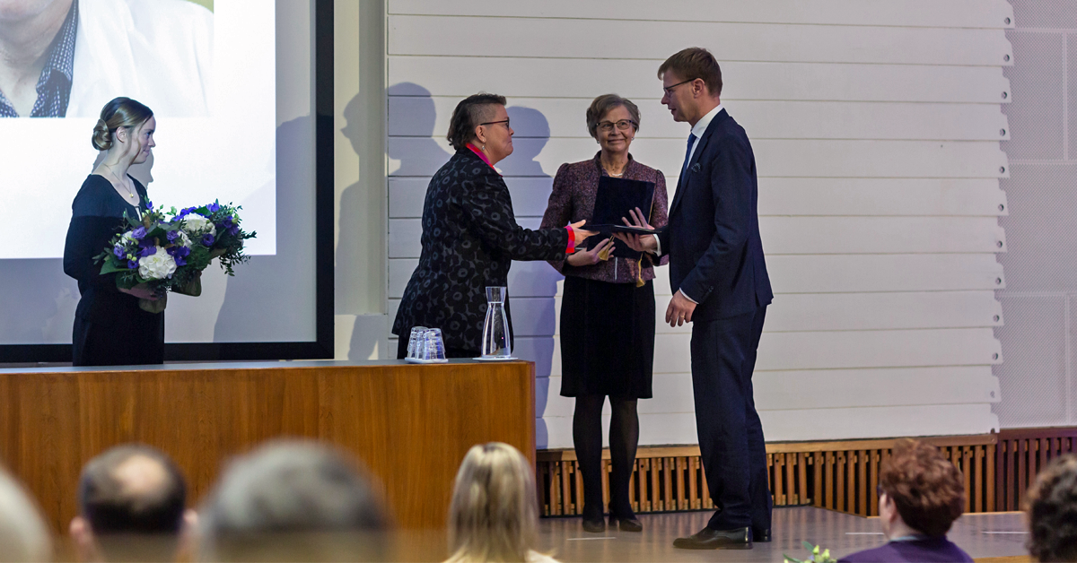 Minna Kaila ojentaa kunniakirjoja Antti Koivistolle ja Riitta Rehuselle.