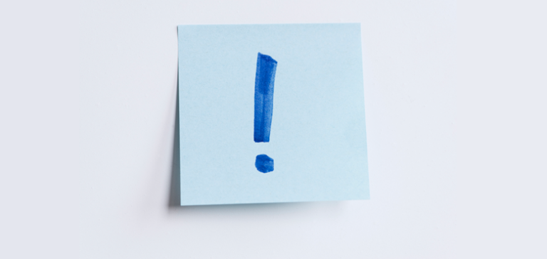 Seinällä vaaleansininen post it -lappu, jossa huutomerkki.