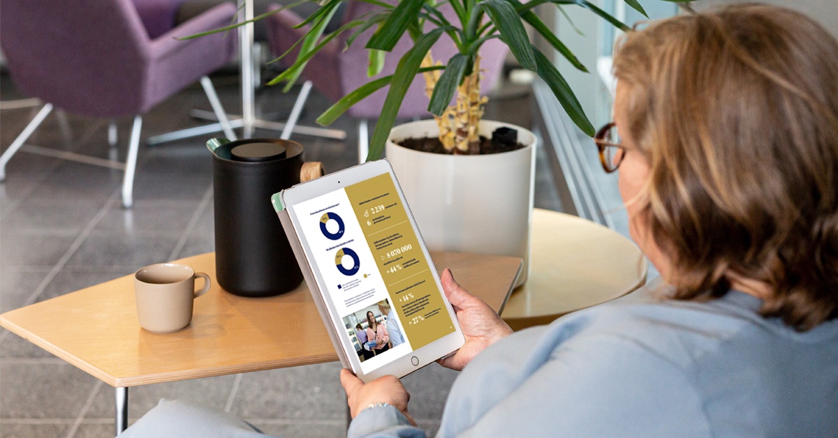 Nainen istuu sohvalla, lukee ipadilta Duodecimin vuosikertomusta vuodelta 2022.