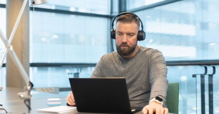 Mies katsomassa webinaaria läppäriltä työpaikalla