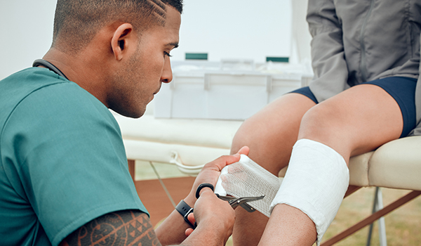 Hoitaja tai lääkäri hoitamassa jalkavammaa